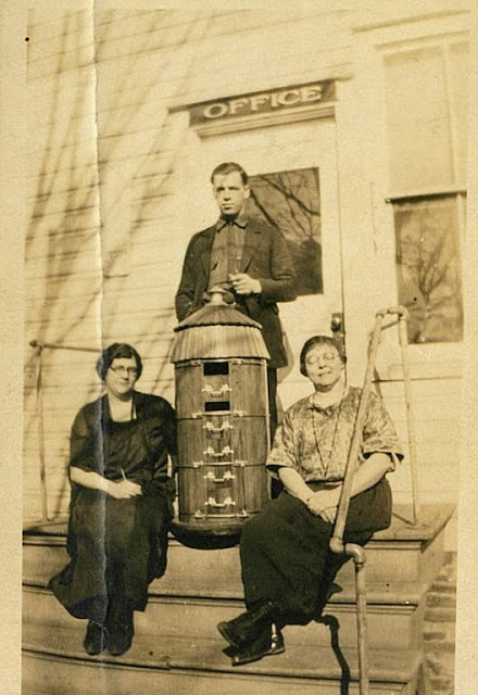 Previous Unalam employees on the front steps of the office with a silo model/