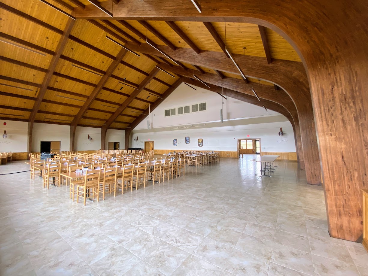 Large hall featuring wood laminate beams and tables set for dining.