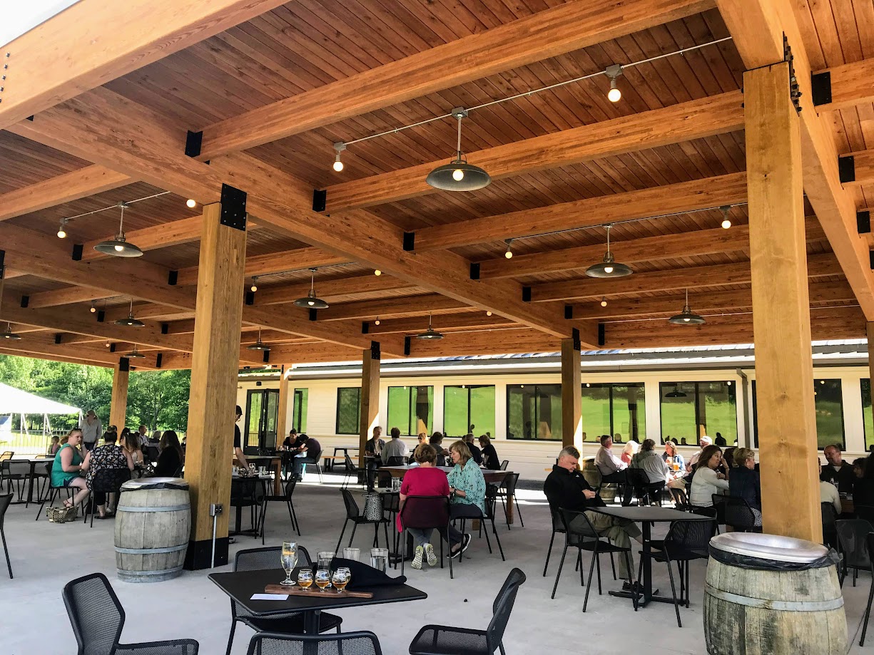 Outdoor dining area featuring wood laminate beams by Unalam, with patrons seated at tables.