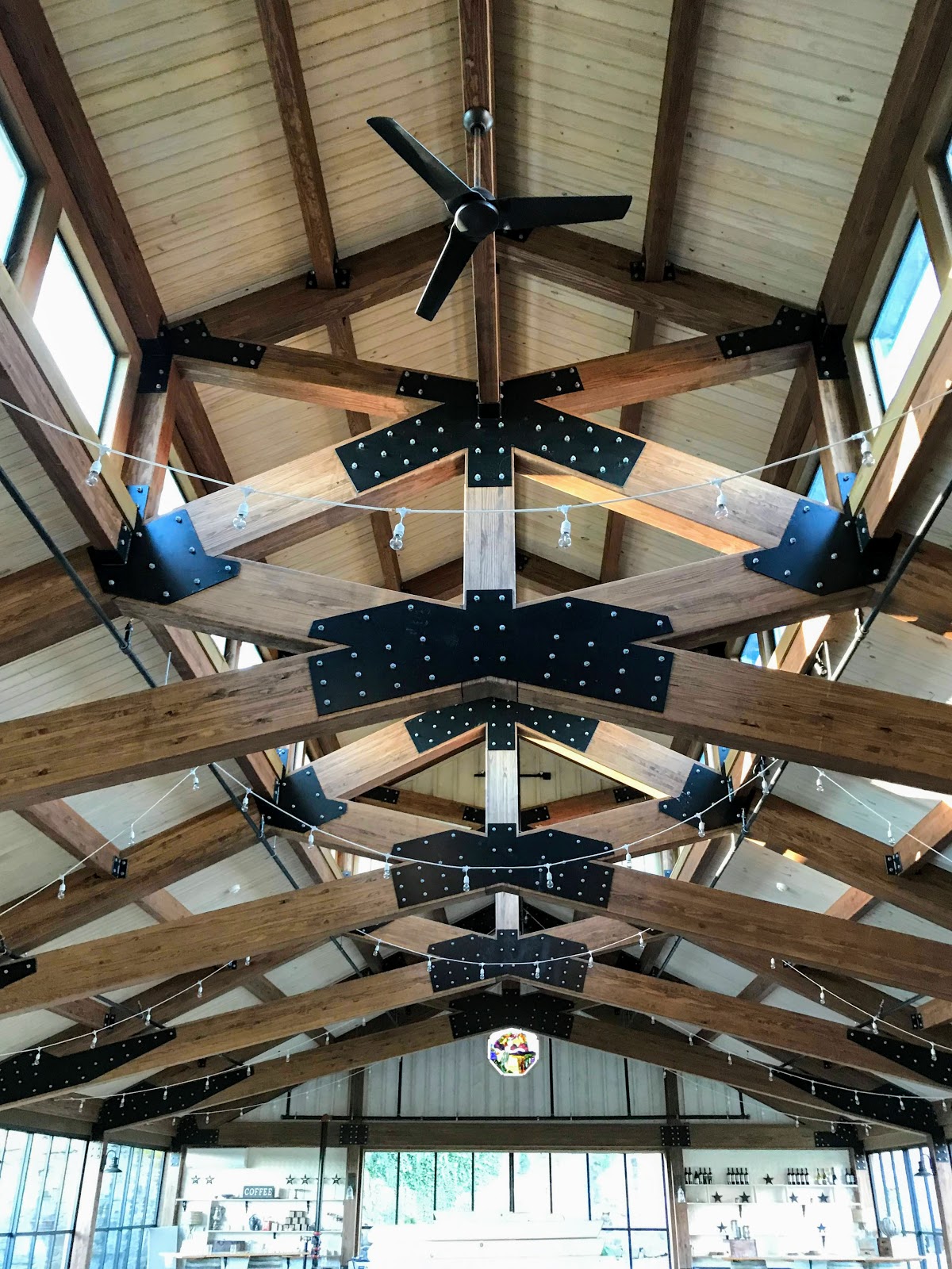 Interior view of a wooden beam ceiling with metal brackets and a ceiling fan.