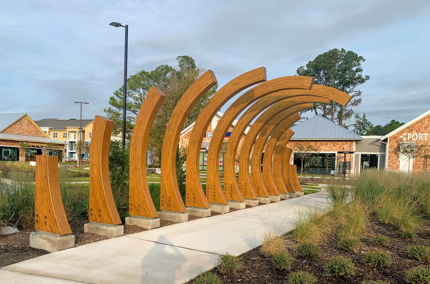Curved wooden beams by Unalam in a landscaped outdoor setting.