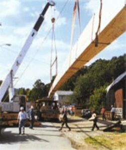 Construction site with cranes lifting wood laminate beams by Unalam.