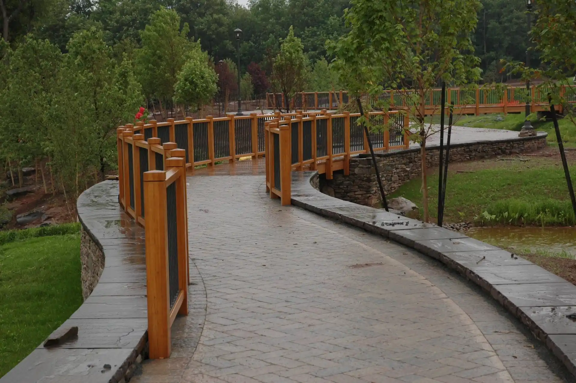 Curved path with Unalam wooden beams and railings in a park setting.