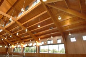 Wood laminate construction beams in a large interior space with windows.