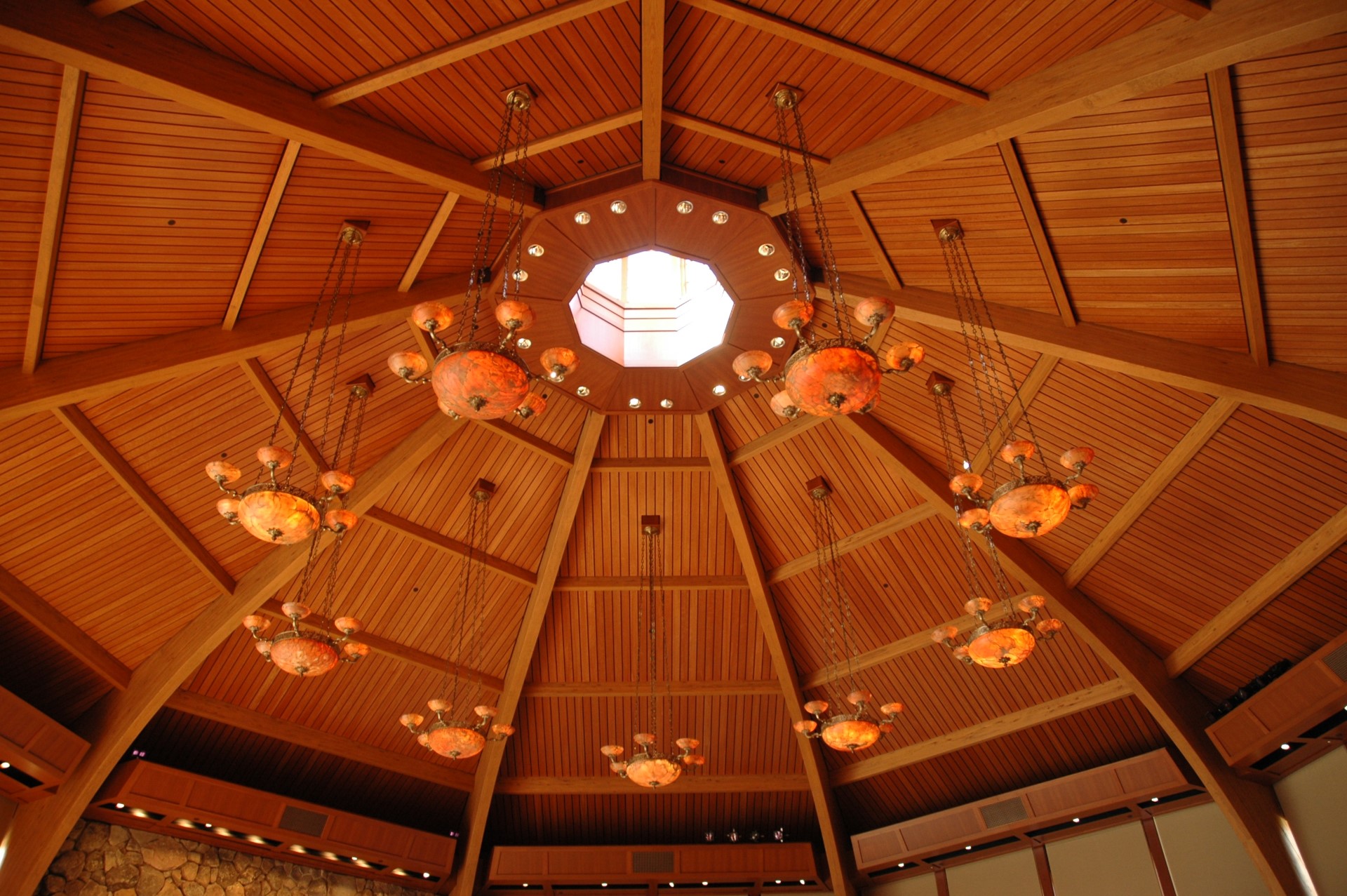 Geometric wooden ceiling with laminate beams and decorative hanging lights.
