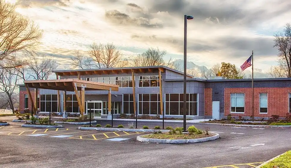 Building with wood laminate beams and large windows, featuring a flagpole.