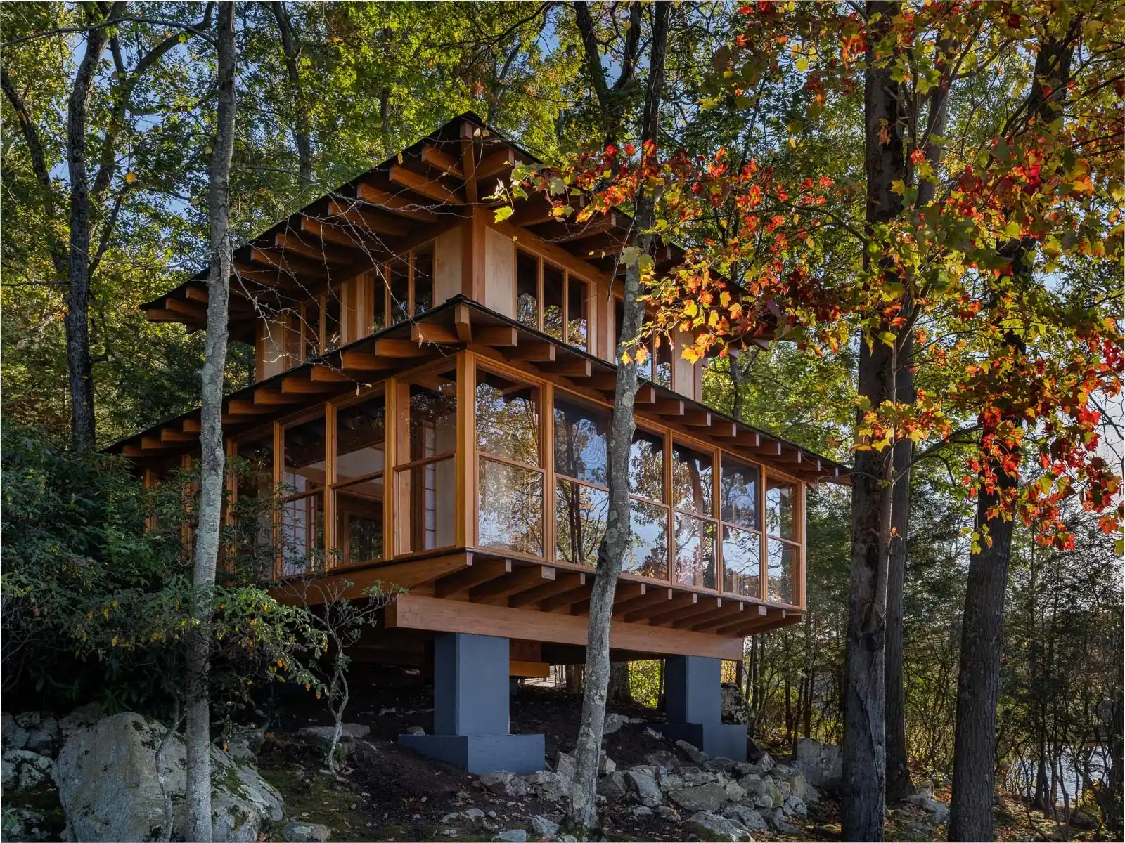 Modern wooden house with laminate beams, surrounded by colorful autumn trees.